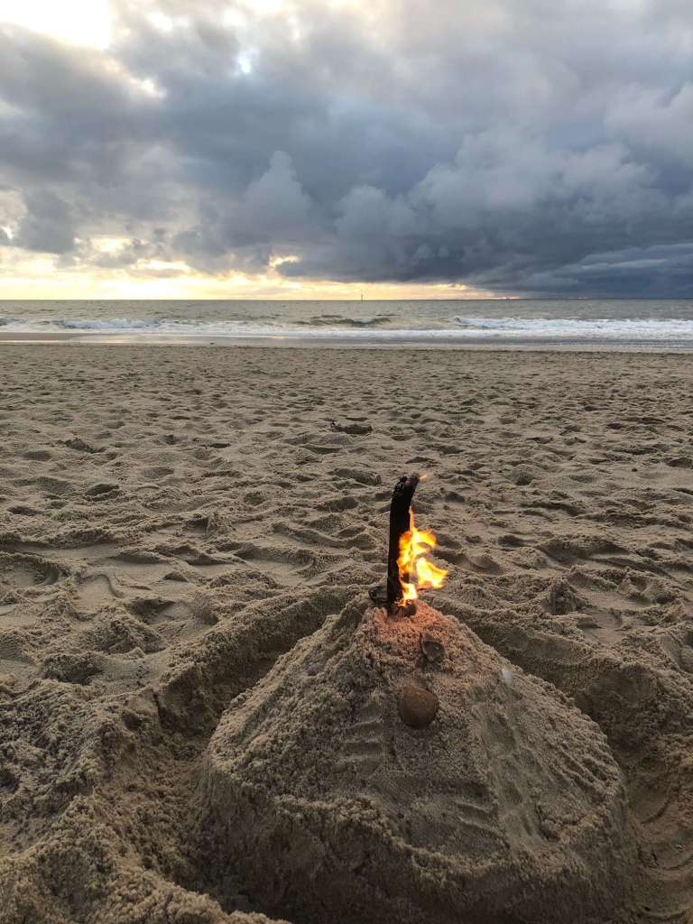 Eine Sandburg am Strand mit einem Feuer darin.