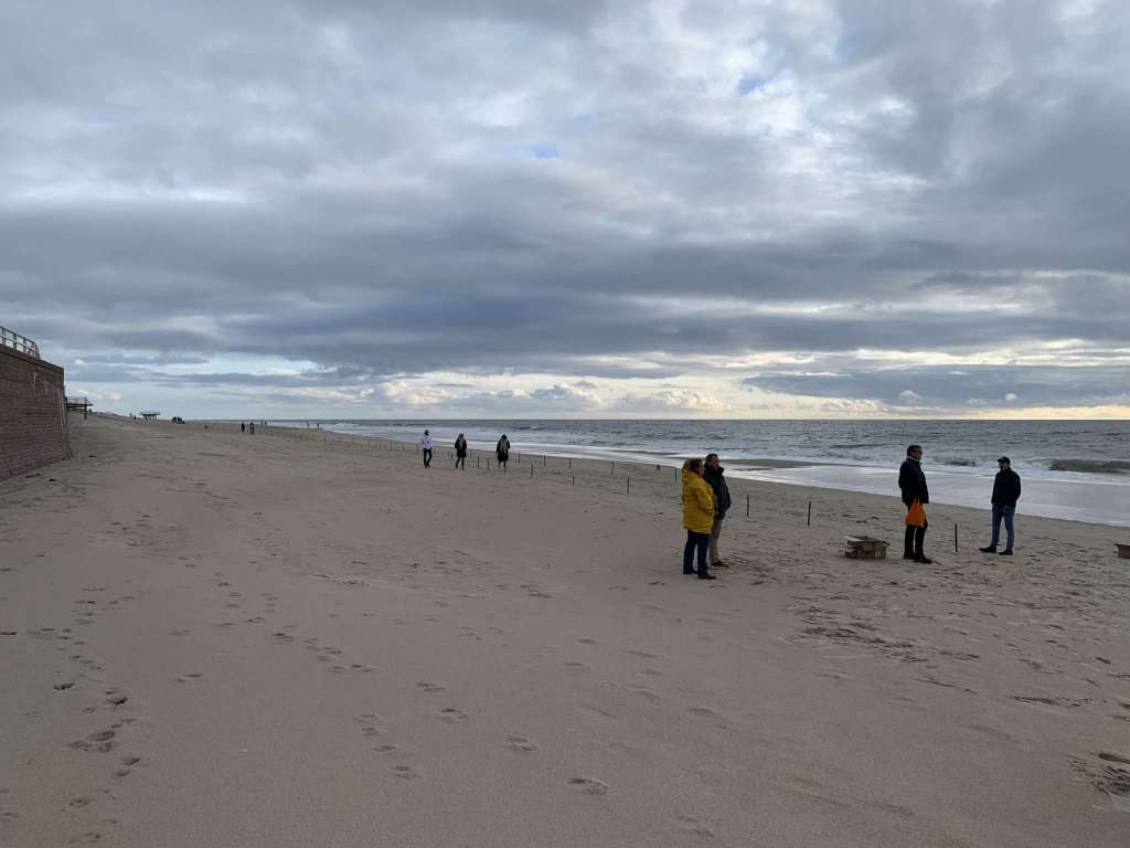 Eine Gruppe von Menschen steht an einem Strand mit bewölktem Himmel.