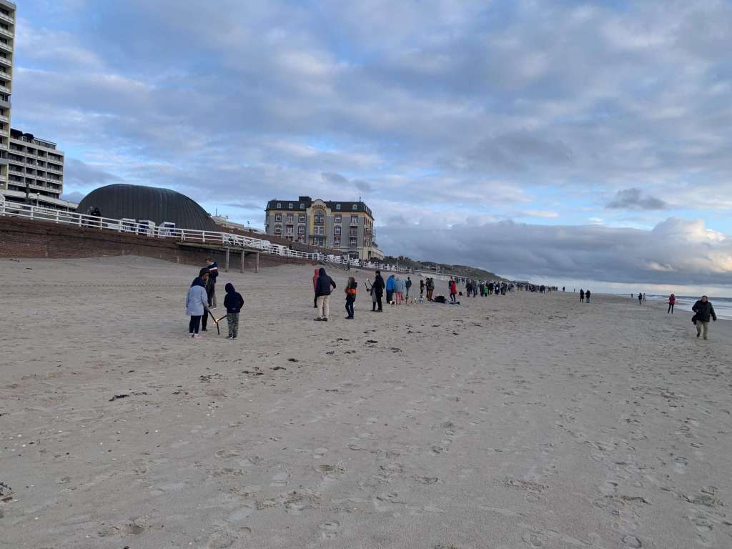 Eine Gruppe von Menschen, die an einem Sandstrand spazieren gehen.