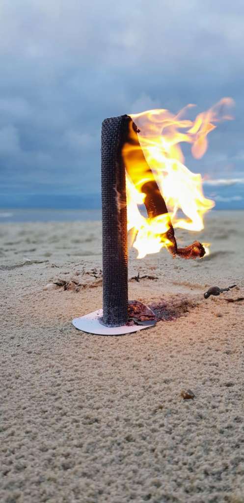 Ein Feuer, das im Sand vor dem Meer brennt.