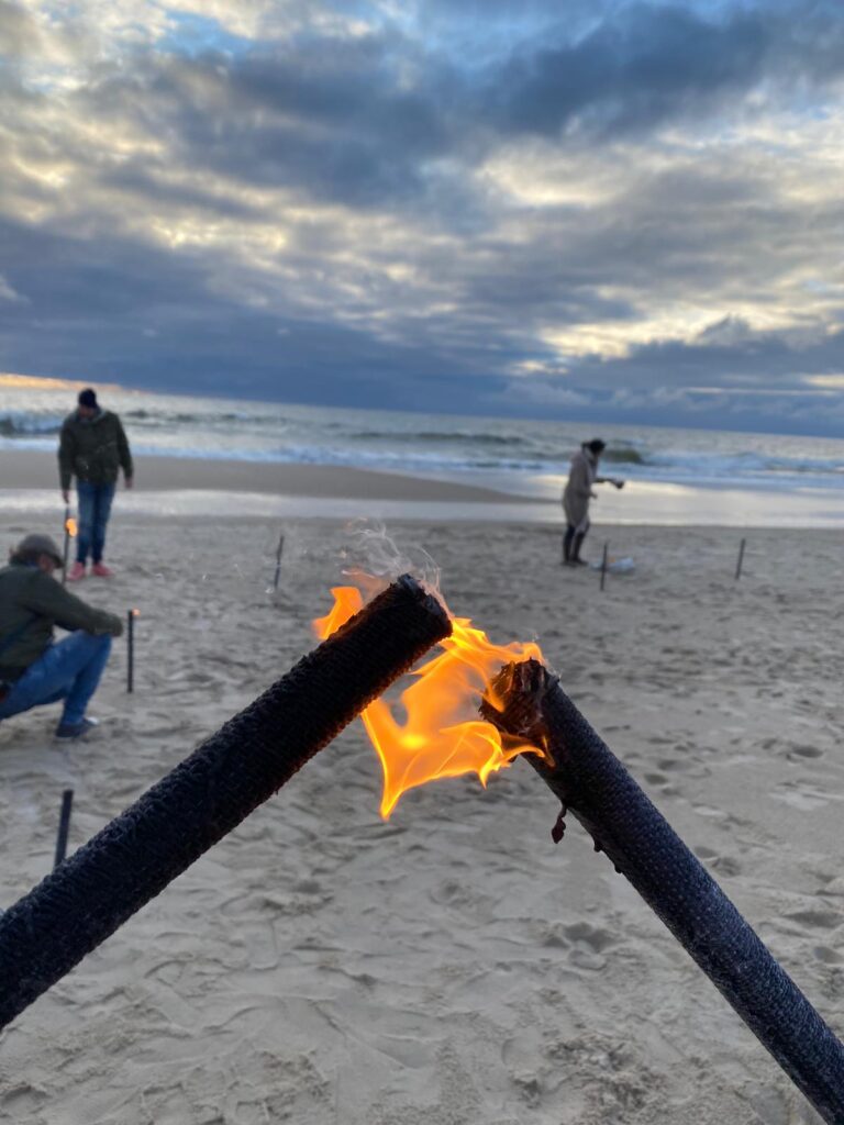 Eine Gruppe von Menschen am Strand mit einem Feuer.